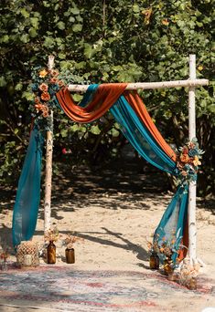 an outdoor wedding ceremony setup with blue and orange draping, flowers and candles