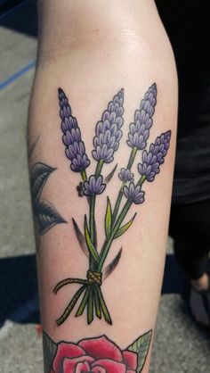 a woman's leg with lavenders and a rose tattoo on her left calf