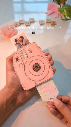 a person holding up a pink camera in their hand