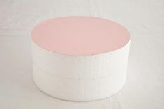 a round pink and white paper container on a white tableclothed surface with the lid off