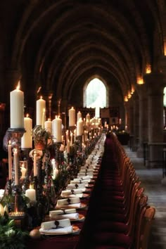 a long table with candles and plates on it in an old cathedral like setting for a formal dinner