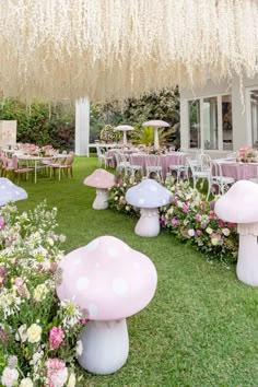 an outdoor party with pink and white decorations on the lawn, tables and chairs covered in flowers