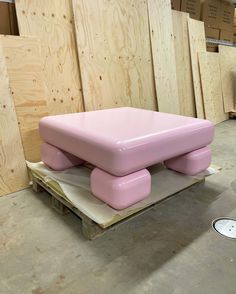 a pink bench sitting on top of a pallet in a room filled with plywood boards