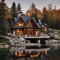 a large house sitting on top of a lake next to a lush green forest filled with trees