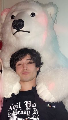 a man with pink hair standing next to a giant teddy bear