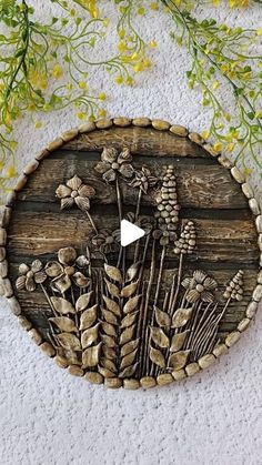 a wooden plaque with flowers and leaves in it on a wall next to yellow flowers