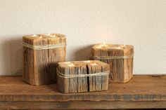 three wooden candle holders sitting on top of a table next to each other with lit candles in them