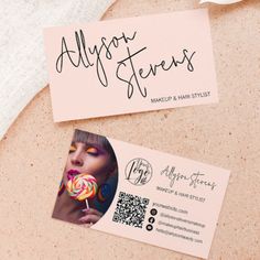 two business cards sitting on top of each other next to a pink envelope with an image of a woman eating a lollipop