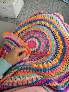 a person is holding a crocheted blanket in their hand while sitting on the couch