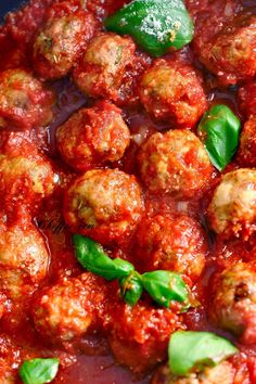 meatballs in tomato sauce with basil leaves on top and green pepper sprigs