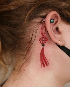 a woman has a tattoo on her ear and behind the ear is a red tatoo