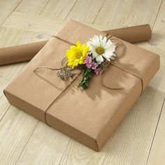 a wrapped gift with flowers on it sitting on the floor next to a roll of brown paper