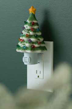 a christmas tree light switch cover is on the wall next to a white electrical outlet