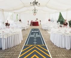 a long table set up with white tables and chairs