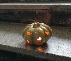 a green pumpkin with glowing eyes and stars on it's face sitting on some steps