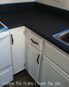 a kitchen with white cabinets and black counter tops is pictured in this image, the sink has blue trim on it