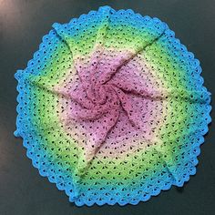 a crocheted doily with a pink and green center