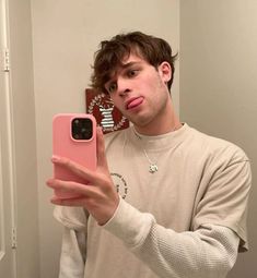 a man taking a selfie in the mirror with his cell phone and tongue sticking out