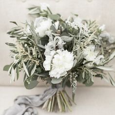 a bouquet of flowers sitting on top of a white couch next to a gray scarf