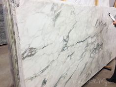 a man standing next to a large white marble slab