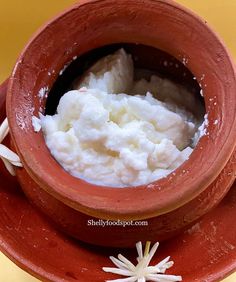 a clay pot filled with white food on top of a red plate next to star decorations