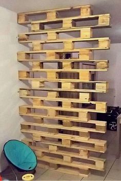 a large stack of wooden pallets sitting on top of a floor next to a blue chair