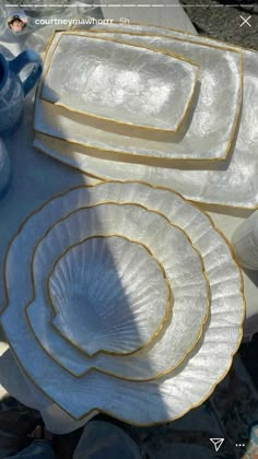 white dishes with gold trim sitting on top of a table next to blue vases