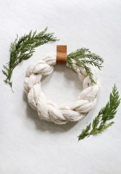 a white rope bracelet with a wooden button on it and some green branches around it