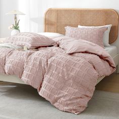 a bed with pink comforter and pillows on it