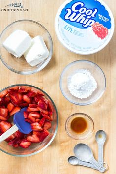 ingredients to make strawberry shortcakes laid out on a wooden table including butter, sugar and strawberries