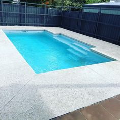 an empty swimming pool in the middle of a backyard with fenced in area around it