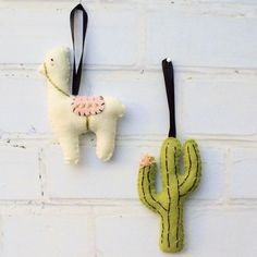 two stuffed llamas hanging on the wall next to a cactus