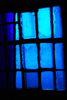 a window with blue and purple glass in it's dark room, showing the light coming through