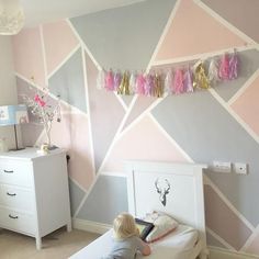 a young child is sitting on a bed in a room with pink and grey walls