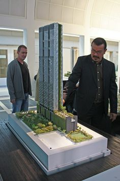 two men looking at a model of a skyscraper