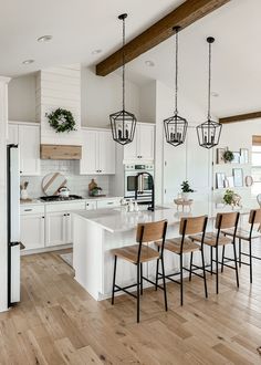 a kitchen filled with lots of white appliances and wooden flooring next to a dining room table