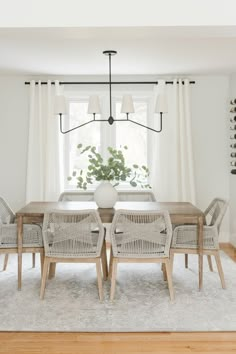 a dining room table and chairs with white curtains