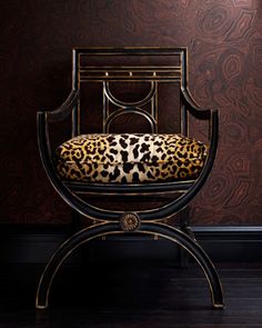 a chair with a leopard print cushion on it in front of a wallpapered background