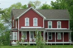 a red house sitting in the middle of a lush green field