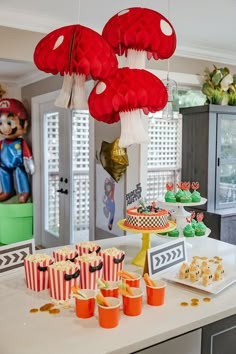 a table topped with cupcakes and cakes covered in red paper lanterns hanging from the ceiling