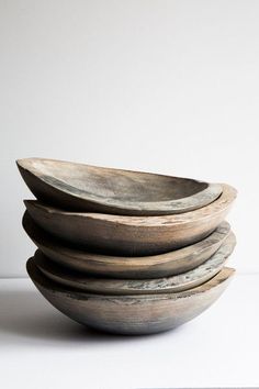 a stack of wooden bowls sitting on top of a white table next to each other