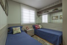 two twin beds in a small room with blue sheets and pillows on the bedding