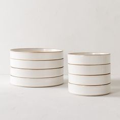 two white bowls sitting next to each other on top of a table with no one around them