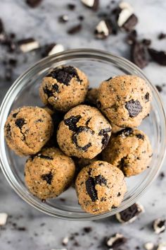 chocolate chip cookies in a glass bowl on a marble counter top with oreos scattered around