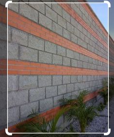 the side of a brick building with plants growing in front of it and a white square frame