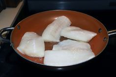 fish being cooked in a frying pan on the stove