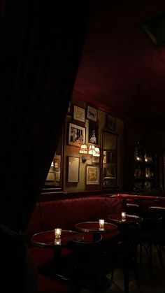 a dimly lit restaurant with red velvet booths and pictures on the wall behind it at night