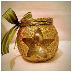 a gold glittered jar with a star on the front and green ribbon around it