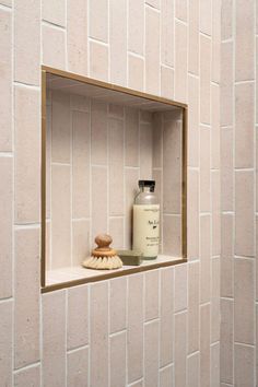 a white tiled bathroom with a shelf for soap and scrubs