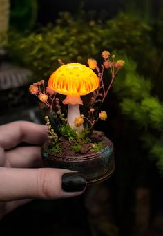 a hand holding a small yellow mushroom light